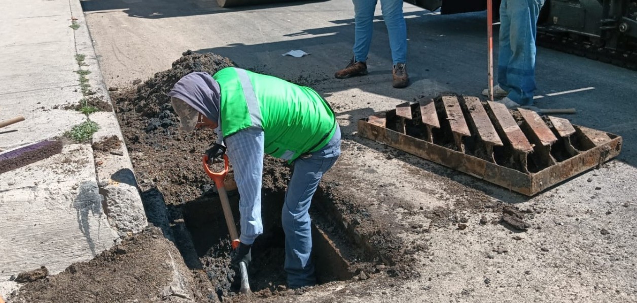 Trabajadores protegen una alcantarilla durante una obra de pavimentación.