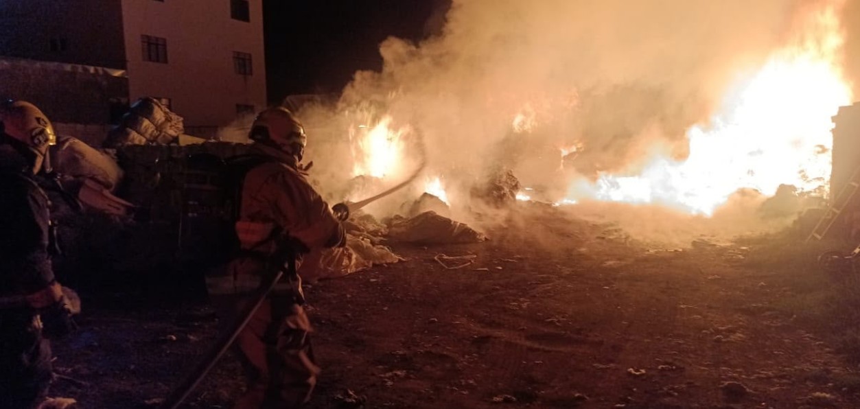 Bomberos trabajan para controlar un incendio en una bodega de material reciclable en Puebla.