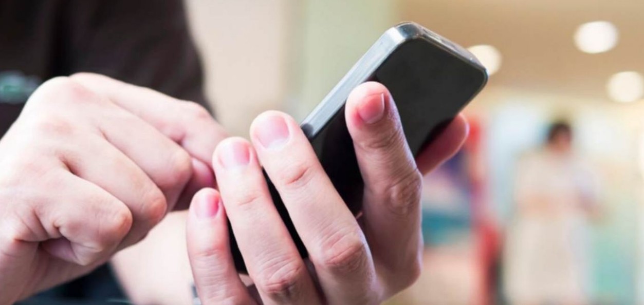 Persona registrando una línea de celular en un dispositivo móvil con documentos de identificación