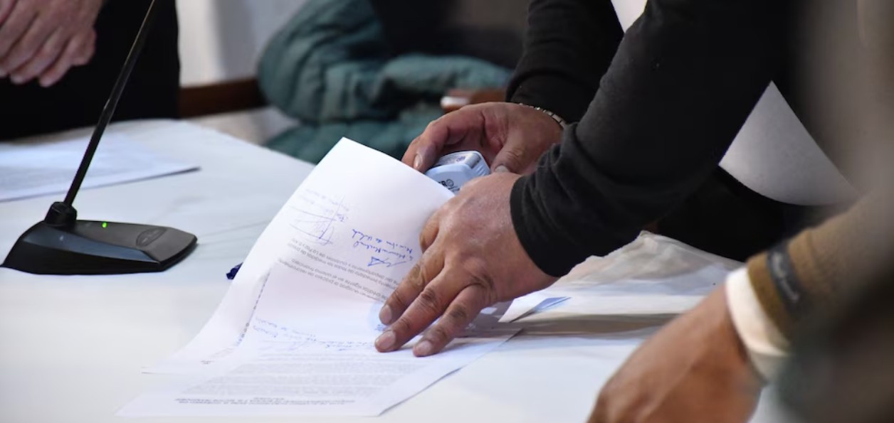 Adulto mayor firmando documentos ante notario