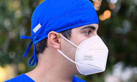 pensive tired young male healthcare worker looking away wearing a n95 protective face mask